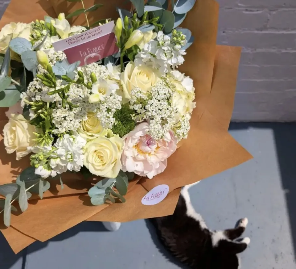 Cream rose, peony and eucalyptus bouquet wrapped in kraft paper