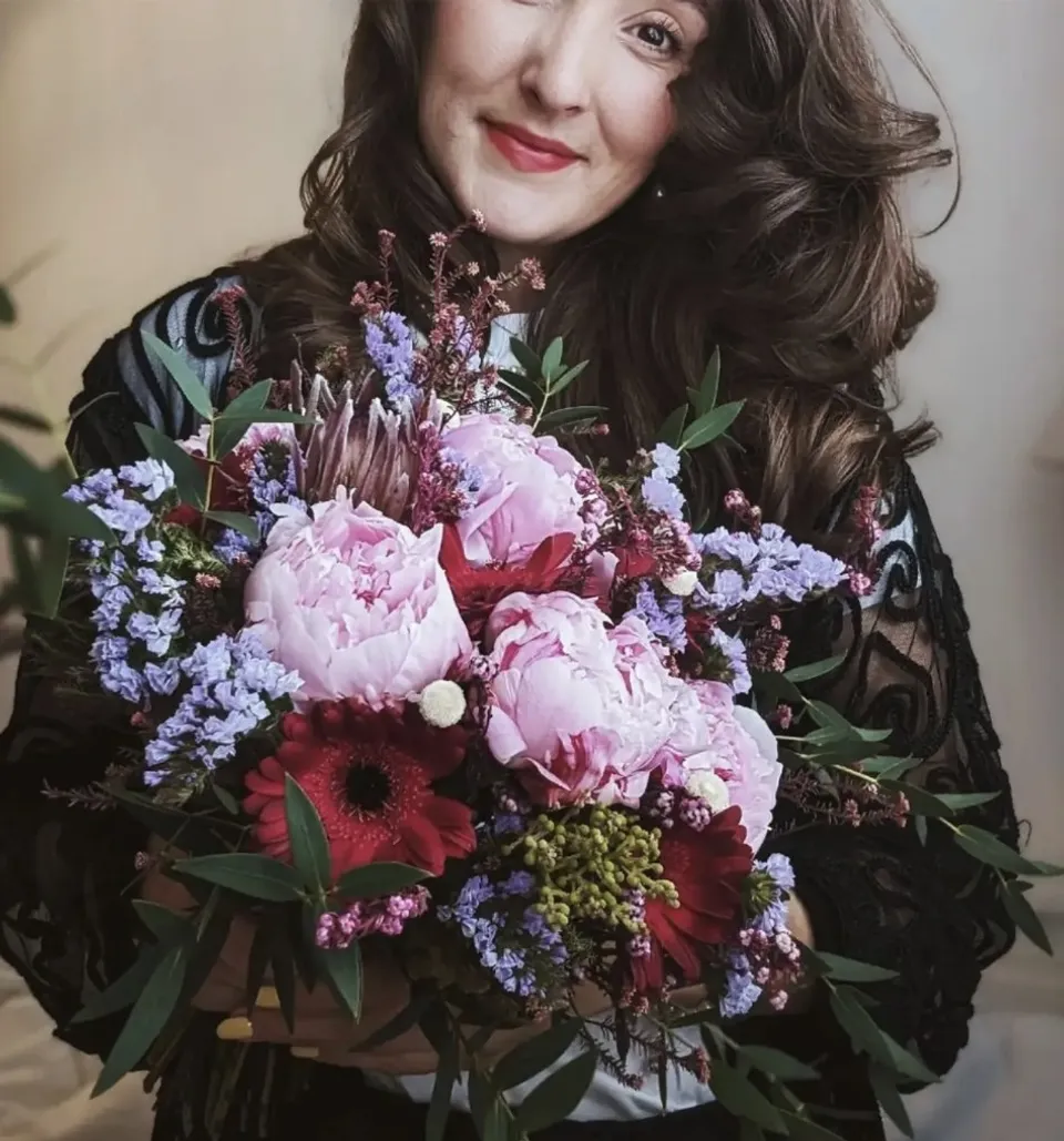 Sophia holding a peony, gerbera and sea lavender bouquet